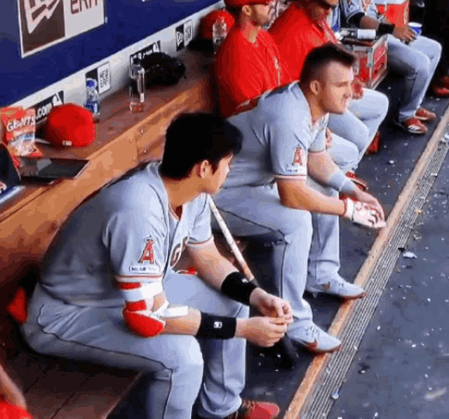 a group of baseball players are sitting in a dugout and one of them has the letter a on their jersey