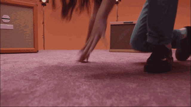 a woman is crawling on the floor in front of an orange box with the letter e on it