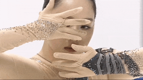 a woman covering her face with her hands wearing gloves with rhinestones on them