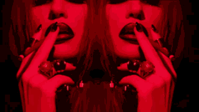 a woman with long black nails is smoking a cigarette in the dark
