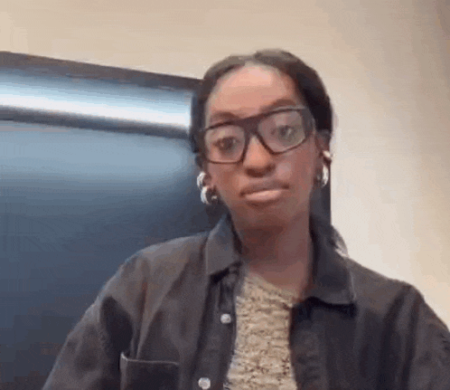 a woman wearing glasses and earrings is making a funny face and looking at the camera .