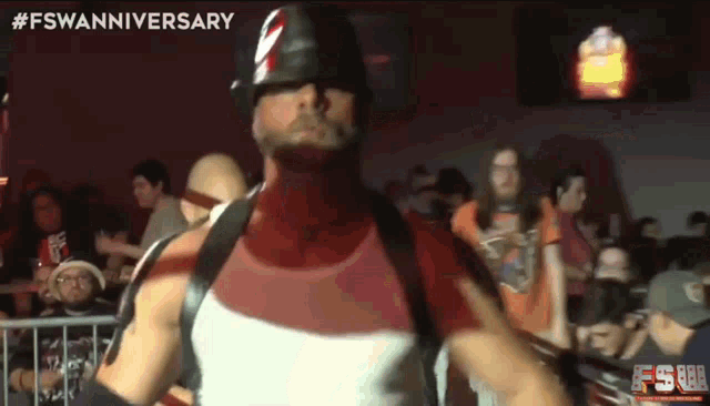 a man in a helmet stands in front of a crowd with the hashtag #fswananniversary on the bottom