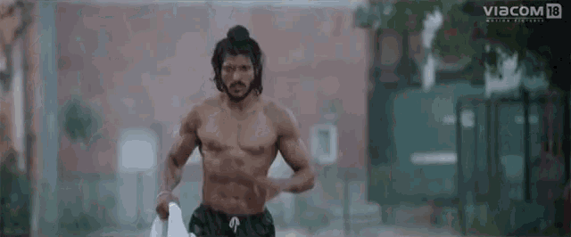 a man without a shirt is running in the rain with a viacom logo behind him