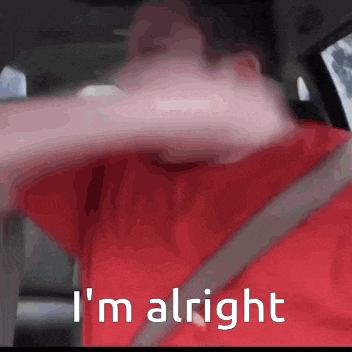 a man in a red shirt is sitting in a car with the words i 'm alright above him