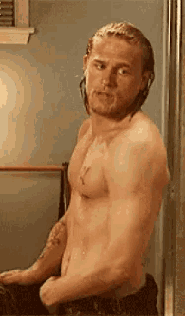 a shirtless man with a beard is standing in front of a mirror .