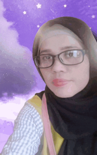 a woman wearing glasses and a hijab poses for a photo