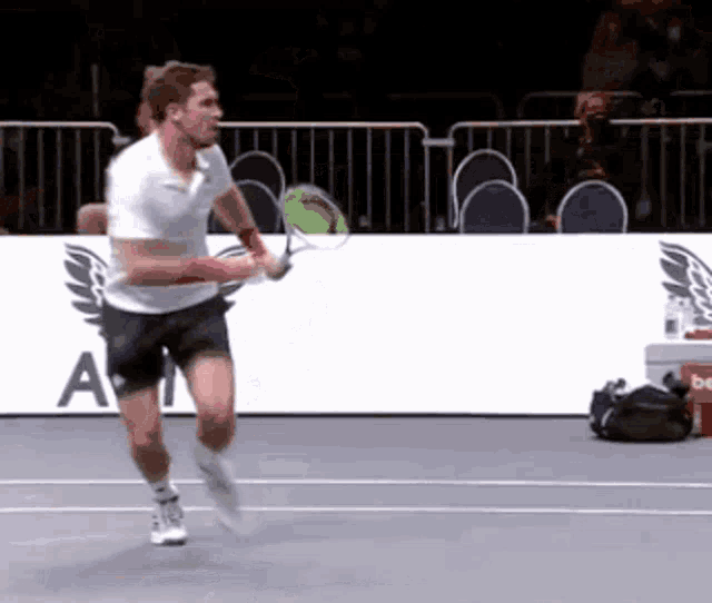 a man is playing tennis on a court with a sign that says a on it