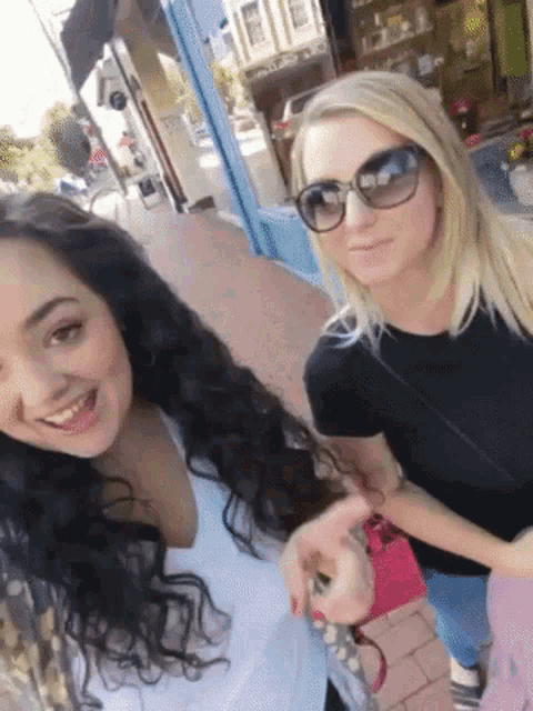 two women standing next to each other wearing sunglasses
