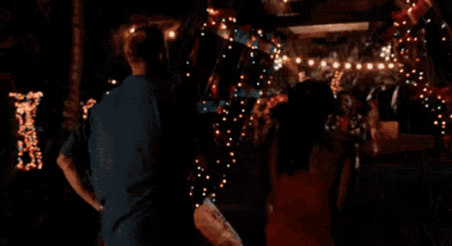a girl in a red dress is dancing in front of a christmas tree