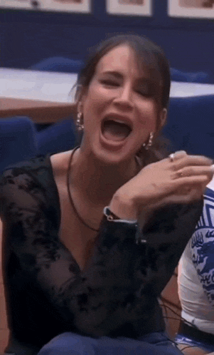 a woman in a black shirt is laughing with her mouth wide open