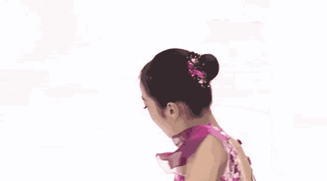 a woman in a pink dress is ice skating on a rink with her arms outstretched .