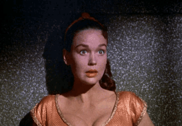 a woman with a surprised look on her face wearing an orange top