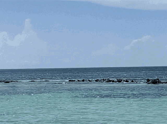 a body of water with rocks in it and a blue sky