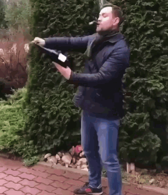 a man in a blue jacket is holding a bottle of champagne in his hands .