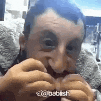 a man with a beard is eating a hamburger with his hands .