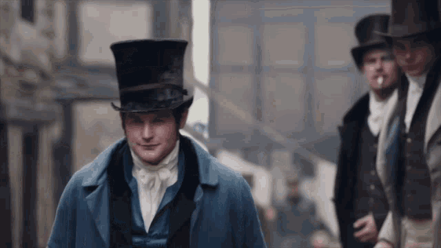 a man wearing a top hat and a blue coat is walking down a street