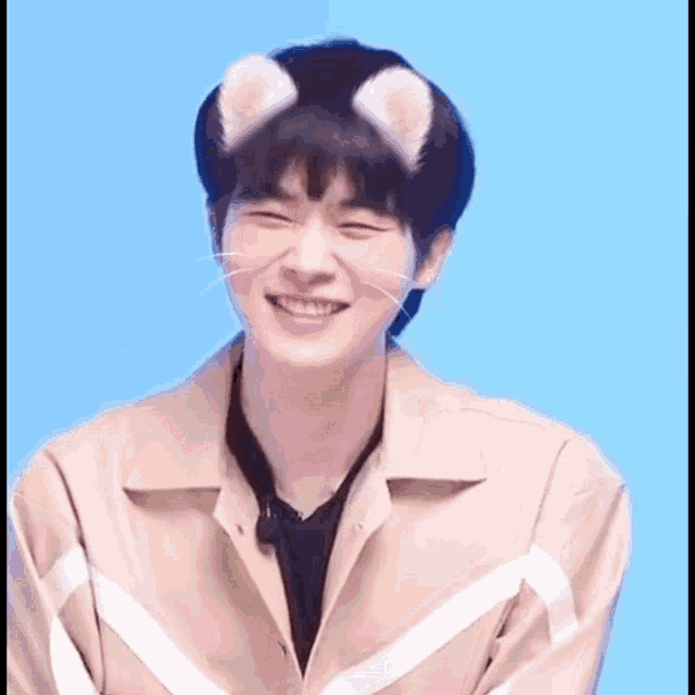 a young man wearing a cat ear headband is smiling and looking at the camera .