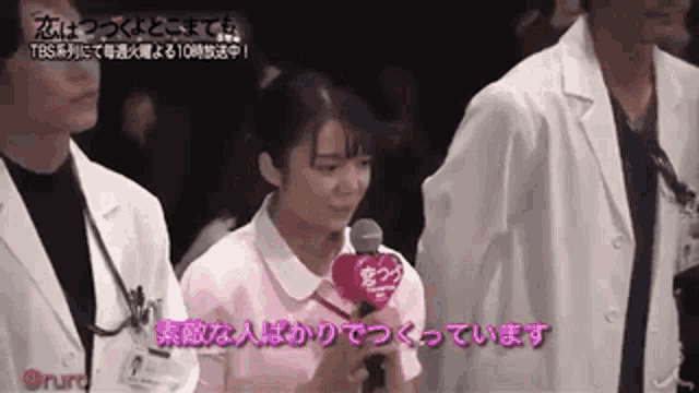 a woman in a pink nurse 's uniform is holding a microphone and speaking into it .