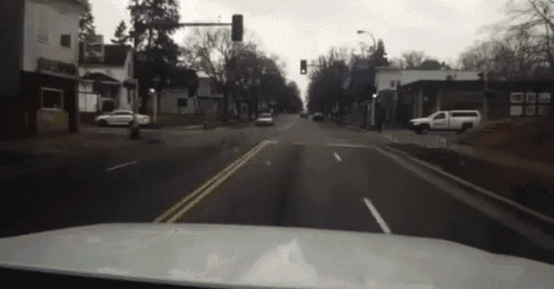 a car is driving down a street with a red light on the right side of the road .