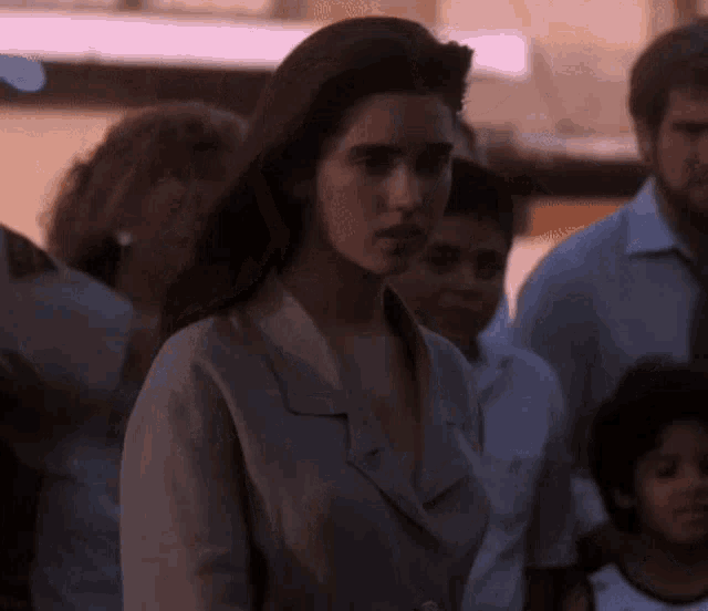 a woman is standing in a crowd of people and looking at the camera