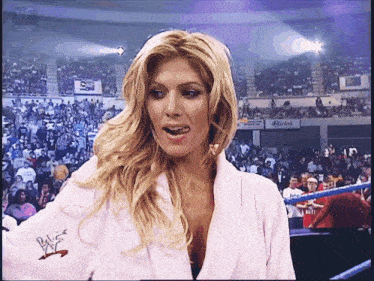 a woman in a pink robe is standing in a wrestling ring with reebok advertisements in the background