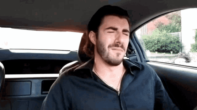 a man with his eyes closed is sitting in a car