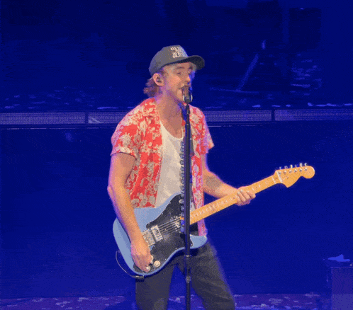 a man playing a guitar and singing into a microphone