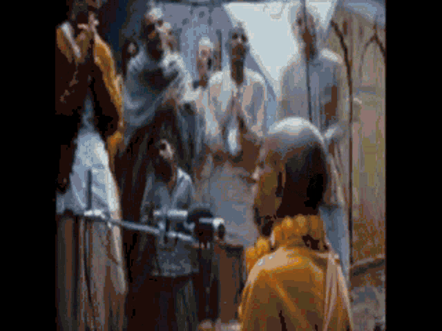 a blurred image of a group of people including a man in a yellow shirt