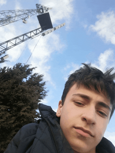 a young man is taking a selfie with a crane in the background