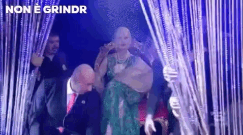 a woman in a green dress is dancing on a stage with a man in a suit and tie behind her .