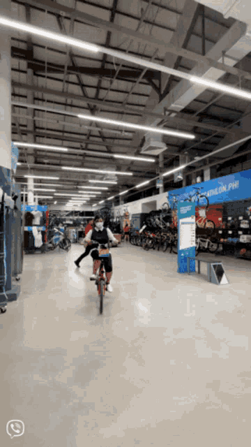 a person is riding a bike in a store with a sign that says decathlon ph