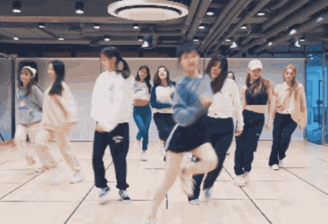 a group of girls are dancing in a room with a ceiling fan
