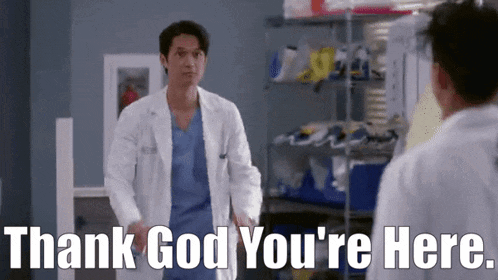 a man in a lab coat is standing next to another man and says thank god you 're here .