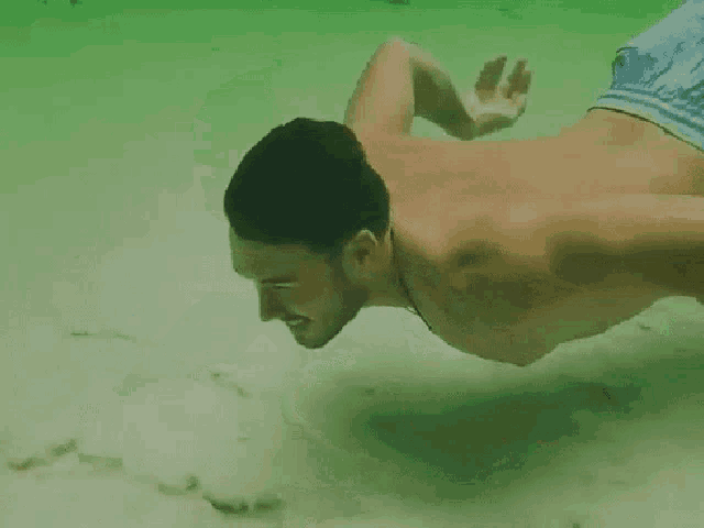 a man without a shirt is swimming in the water
