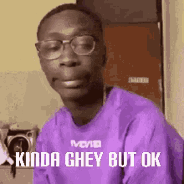 a man wearing glasses and a purple shirt is making a face .