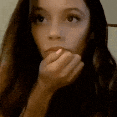 a close up of a woman covering her mouth with her hands