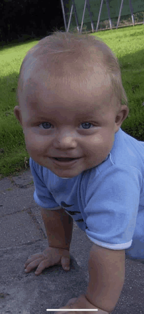 a baby wearing a blue nike shirt is crawling on the sidewalk
