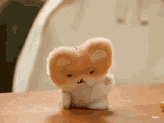 a stuffed animal is sitting on top of a wooden table .