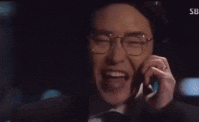 a man wearing glasses and a hat is smiling while talking on a cell phone