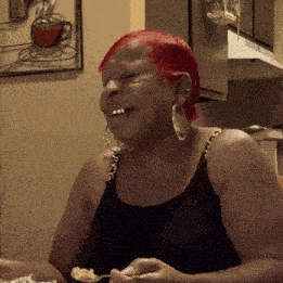 a woman with red hair is sitting at a table with a spoon in her mouth