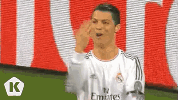 a soccer player wearing a white emirates jersey is waving his hand .