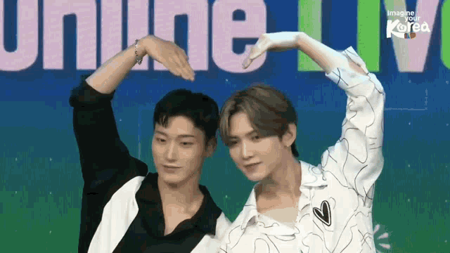 two young men are making a heart shape with their hands in front of the word imagine your korea