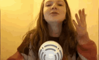 a young woman is holding a white ball in her hand and making a funny face .