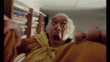 a man with a shocked look on his face stands in front of a bookshelf