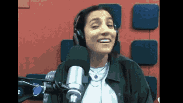 a woman wearing headphones and a microphone is smiling