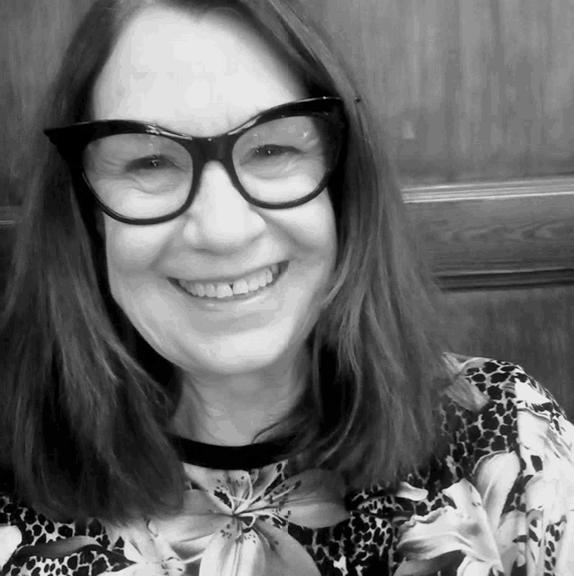 a woman wearing glasses and a floral shirt is smiling