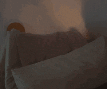 a person is laying on a bed with a clock on the wall behind them