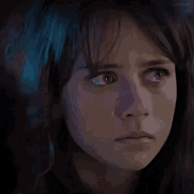 a close up of a woman 's face in a dark room .