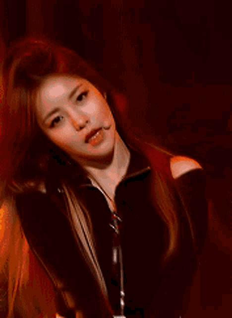 a woman with long red hair is wearing a black top with a zipper