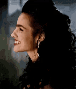 a woman wearing earrings is smiling and looking to the side .